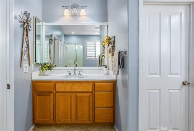 bathroom with a stall shower, vanity, and baseboards
