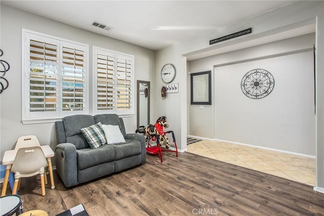 living area with visible vents, baseboards, and wood finished floors