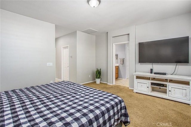 carpeted bedroom with visible vents, baseboards, and connected bathroom