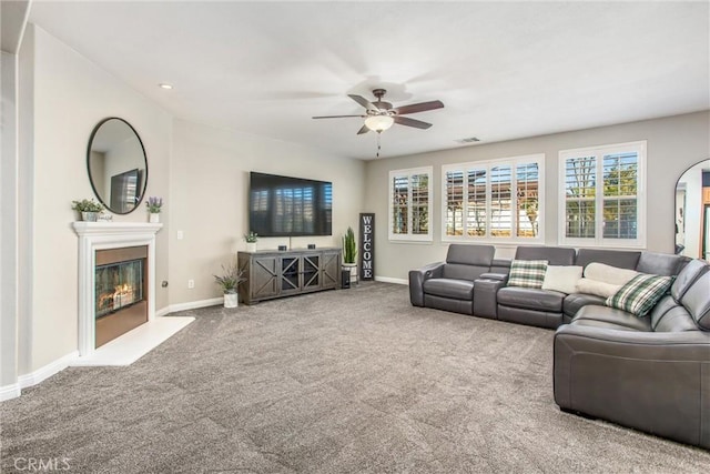 living room with carpet flooring, baseboards, a ceiling fan, and a glass covered fireplace