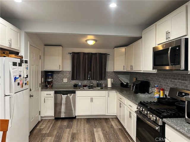 kitchen with white cabinets, dark hardwood / wood-style flooring, stainless steel appliances, decorative backsplash, and sink