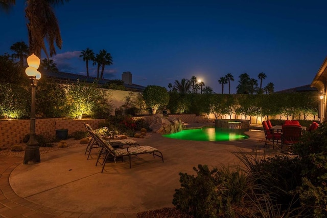 pool at twilight with a patio area