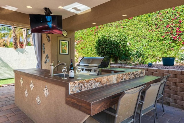 view of patio / terrace featuring exterior kitchen, an outdoor wet bar, and area for grilling