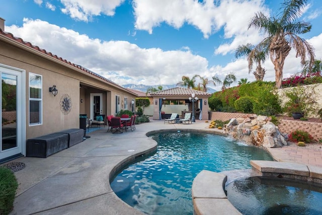 view of swimming pool with pool water feature, a gazebo, a patio area, and an in ground hot tub