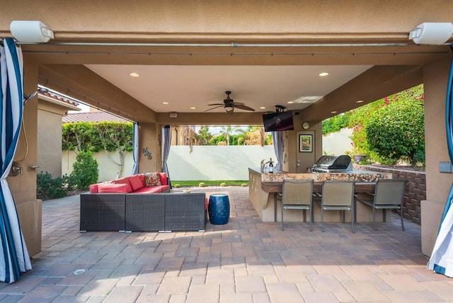 view of patio featuring ceiling fan, an outdoor living space, area for grilling, exterior kitchen, and a bar