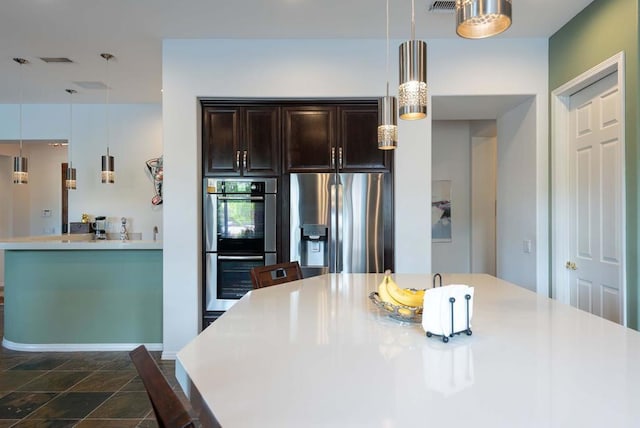 kitchen with appliances with stainless steel finishes, dark brown cabinets, and decorative light fixtures