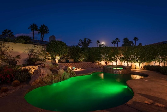 pool at twilight featuring an in ground hot tub