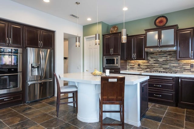 kitchen with decorative light fixtures, a center island, decorative backsplash, a breakfast bar area, and stainless steel appliances