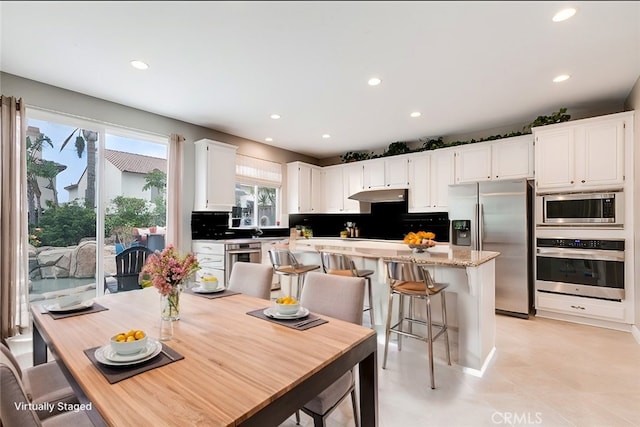 kitchen with a breakfast bar area, white cabinetry, tasteful backsplash, appliances with stainless steel finishes, and a kitchen island