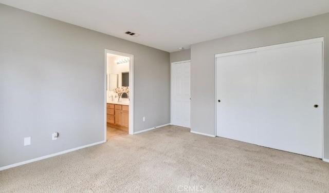 unfurnished bedroom with connected bathroom, light colored carpet, and a closet