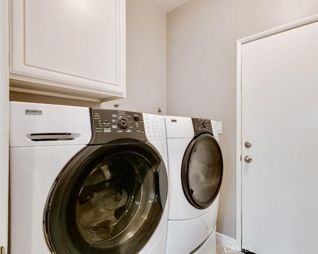 clothes washing area featuring cabinets and washer and dryer