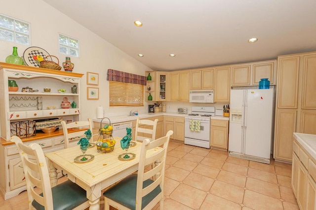 kitchen with light tile patterned floors, lofted ceiling, light brown cabinets, and white appliances