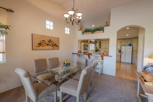 dining area featuring an inviting chandelier, light tile patterned flooring, and a towering ceiling