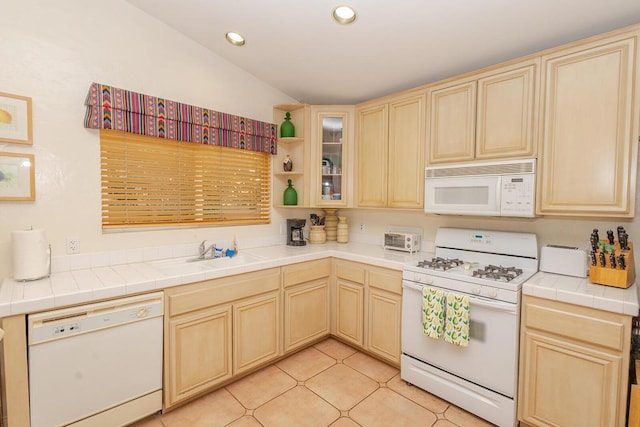 kitchen featuring white appliances, tile counters, light brown cabinets, sink, and light tile patterned flooring