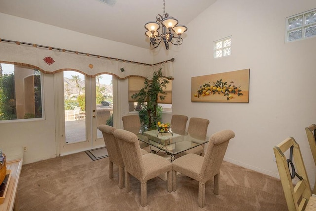 dining area featuring high vaulted ceiling, light colored carpet, french doors, and an inviting chandelier