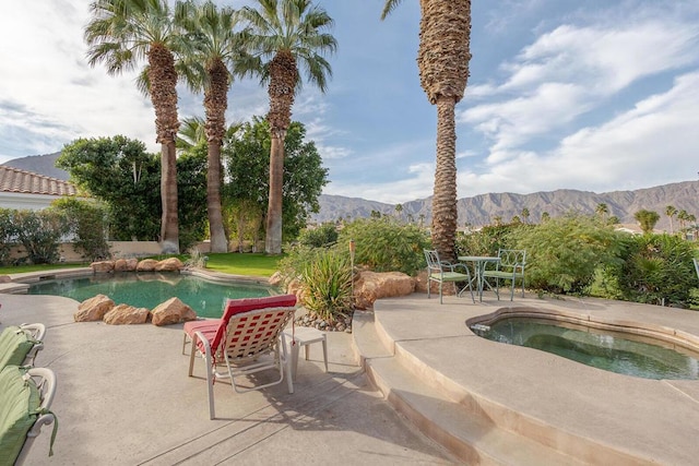 view of swimming pool featuring a jacuzzi, a mountain view, and a patio