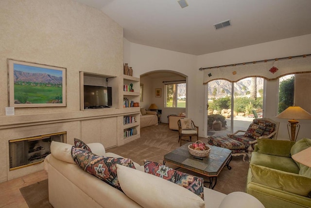 living room featuring a fireplace, vaulted ceiling, and built in features