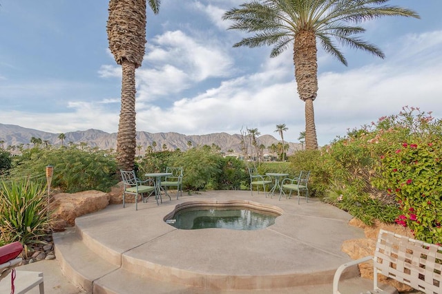 view of pool with a hot tub, a mountain view, and a patio