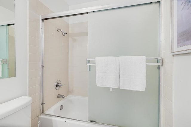 bathroom with bath / shower combo with glass door and toilet