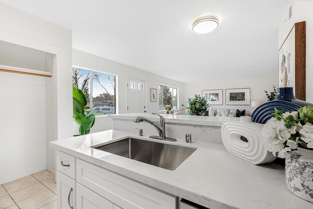 kitchen with white cabinetry, sink, light tile patterned floors, and light stone countertops