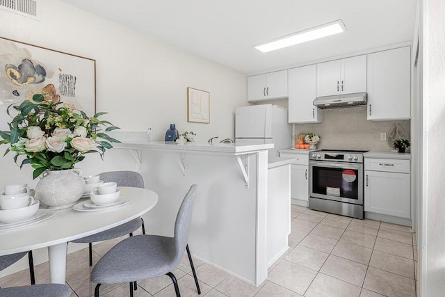 kitchen with white refrigerator, a breakfast bar area, white cabinets, and stainless steel range with electric cooktop