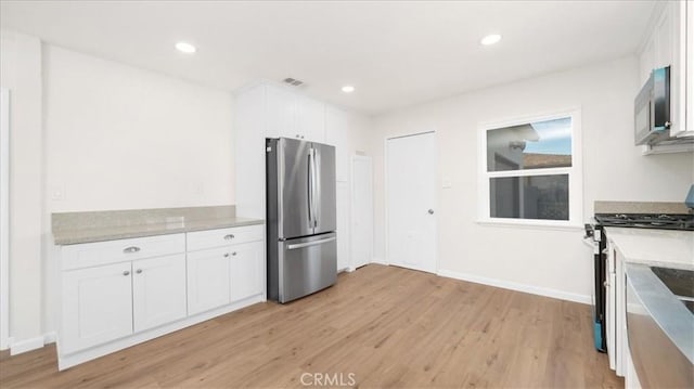 kitchen with stainless steel appliances, light hardwood / wood-style flooring, white cabinets, and light stone countertops