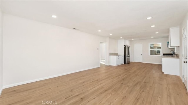 unfurnished living room with light hardwood / wood-style floors and sink