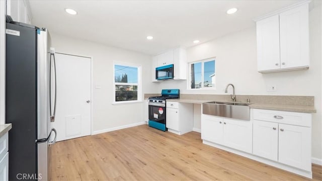 kitchen featuring stainless steel appliances, light hardwood / wood-style flooring, white cabinets, and sink