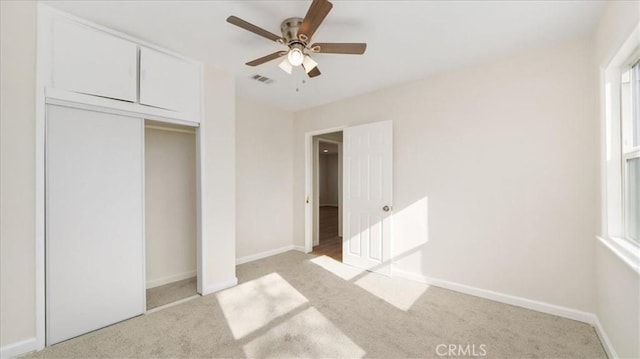 unfurnished bedroom featuring light carpet, ceiling fan, and a closet