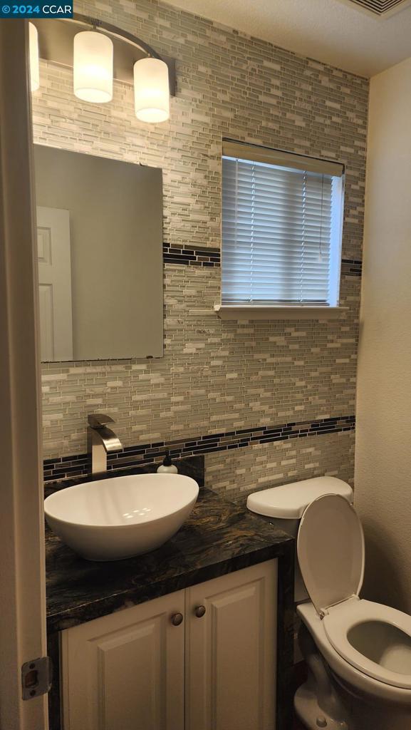 bathroom featuring tasteful backsplash, vanity, and toilet