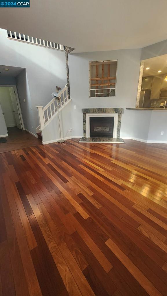 unfurnished living room with a fireplace and dark wood-type flooring