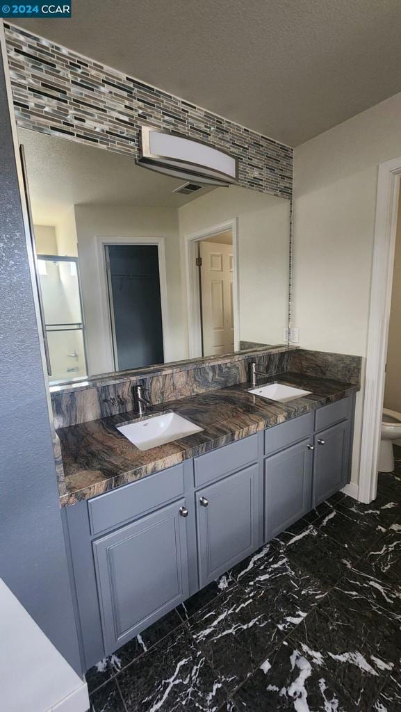 bathroom featuring toilet, a textured ceiling, and vanity