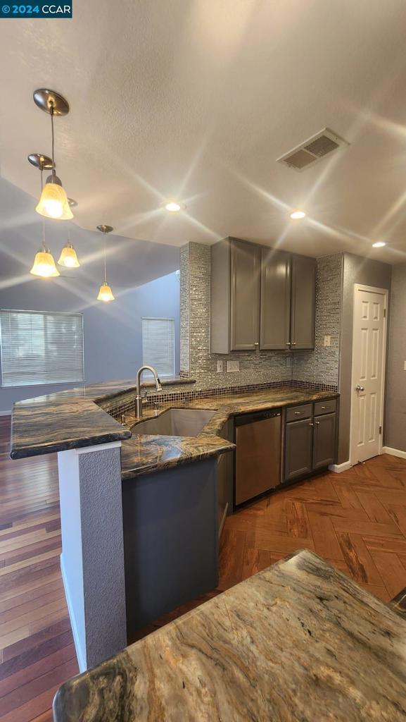 kitchen featuring sink, hanging light fixtures, backsplash, kitchen peninsula, and stainless steel dishwasher