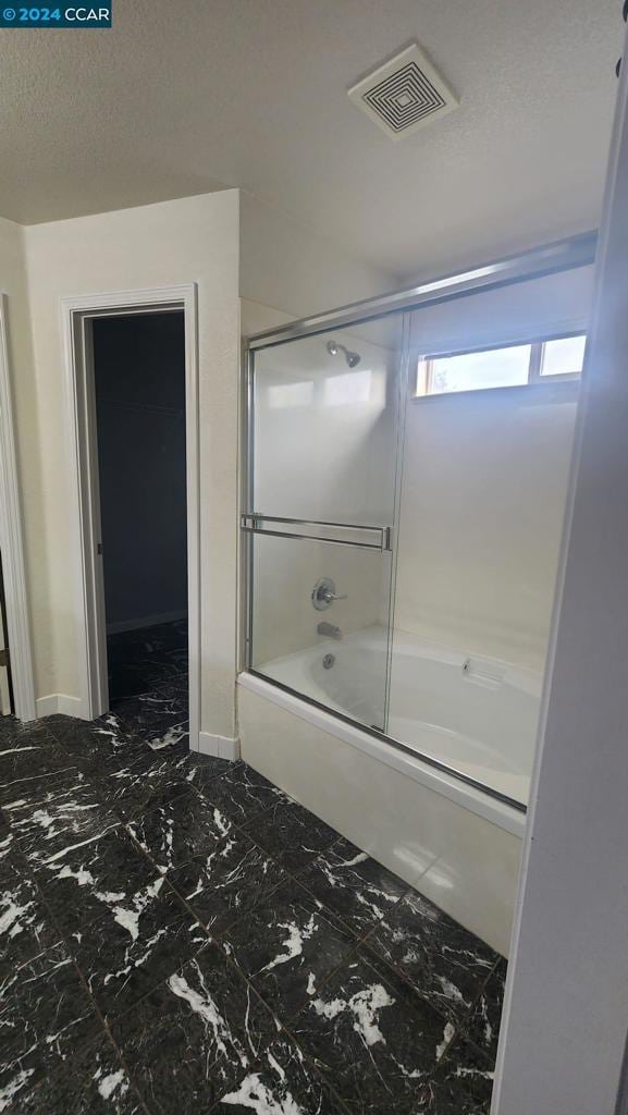 bathroom featuring a textured ceiling and enclosed tub / shower combo