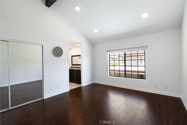 interior space with wood-type flooring, beamed ceiling, connected bathroom, high vaulted ceiling, and a closet