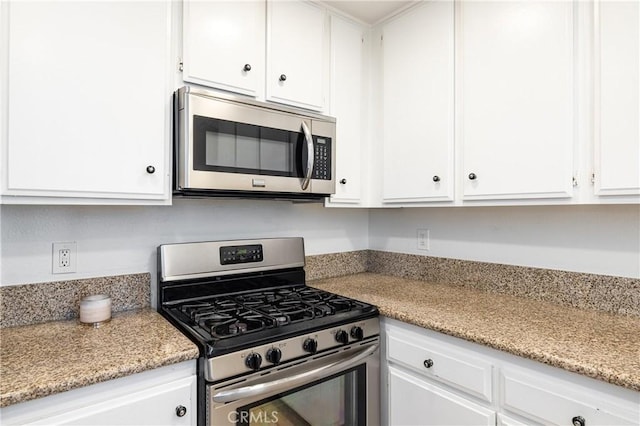 kitchen with light stone counters, white cabinets, and stainless steel appliances