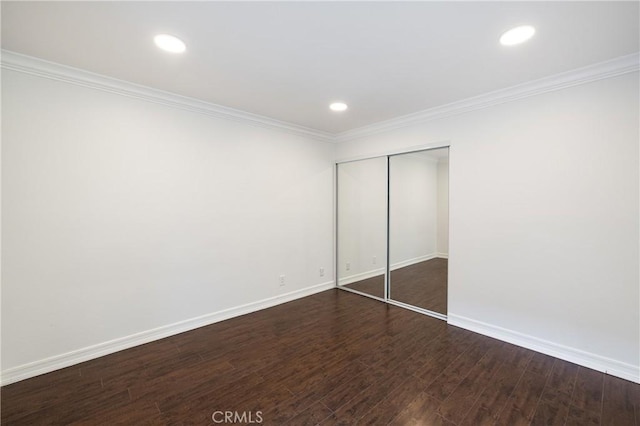 unfurnished bedroom featuring a closet, crown molding, and dark hardwood / wood-style floors