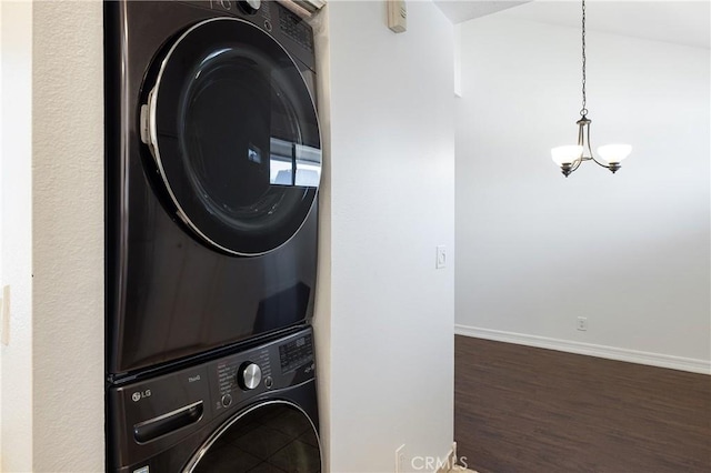 laundry room featuring stacked washer and dryer, dark hardwood / wood-style flooring, and a chandelier