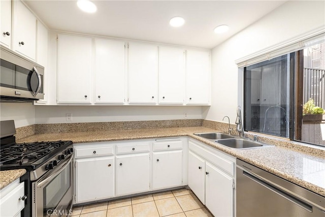 kitchen featuring light tile patterned flooring, appliances with stainless steel finishes, white cabinets, and sink