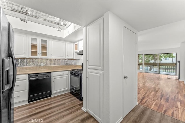 kitchen featuring hardwood / wood-style floors, black appliances, white cabinetry, a skylight, and tasteful backsplash