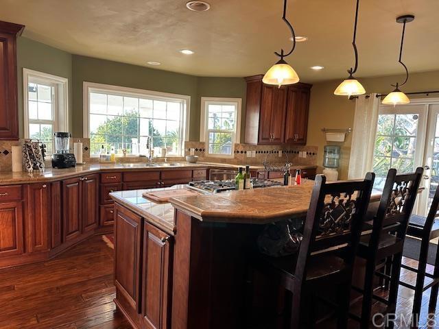 kitchen with backsplash, a center island, pendant lighting, a breakfast bar, and sink