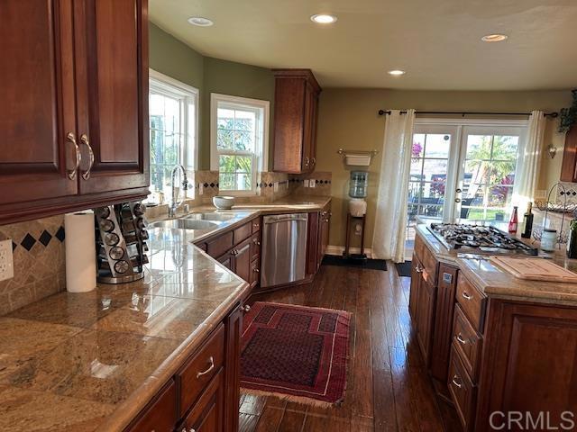 kitchen with sink, backsplash, dark hardwood / wood-style flooring, and stainless steel appliances