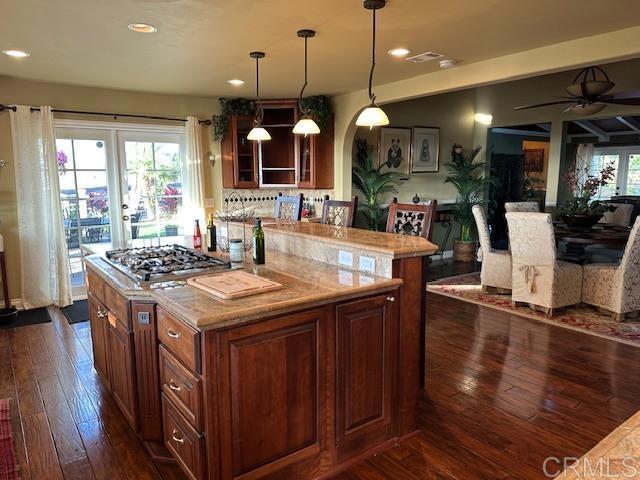 kitchen with hanging light fixtures, stainless steel gas cooktop, ceiling fan, and a center island