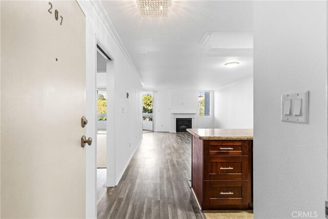 corridor featuring wood-type flooring, an inviting chandelier, and crown molding