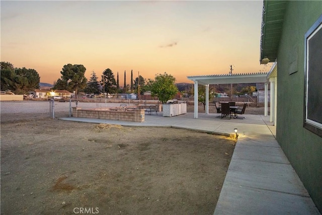 yard at dusk featuring a pergola and a patio