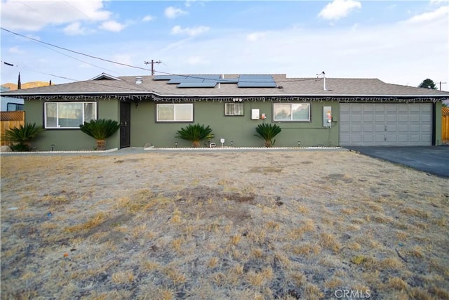 ranch-style house with a garage and solar panels