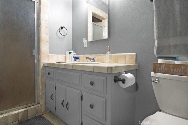 bathroom featuring toilet, tasteful backsplash, tile patterned floors, an enclosed shower, and vanity