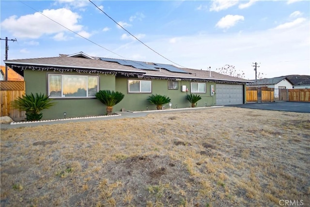 single story home featuring solar panels and a garage