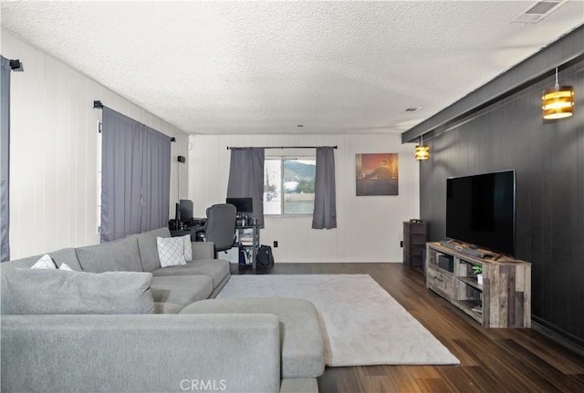 living room featuring dark hardwood / wood-style floors, wood walls, and a textured ceiling