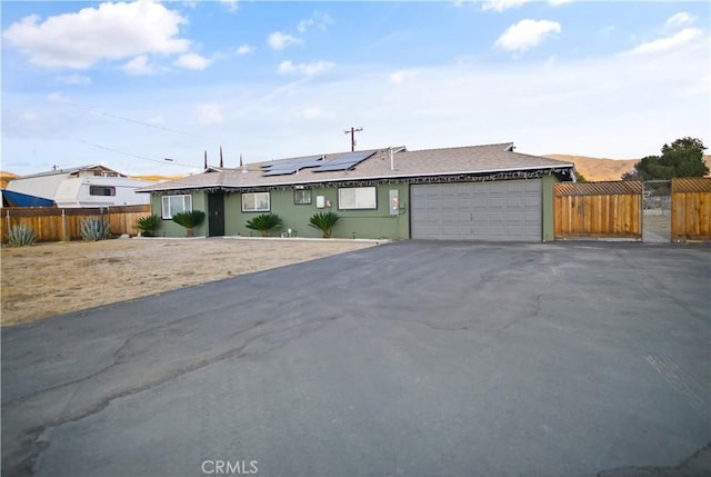 single story home with a garage and solar panels